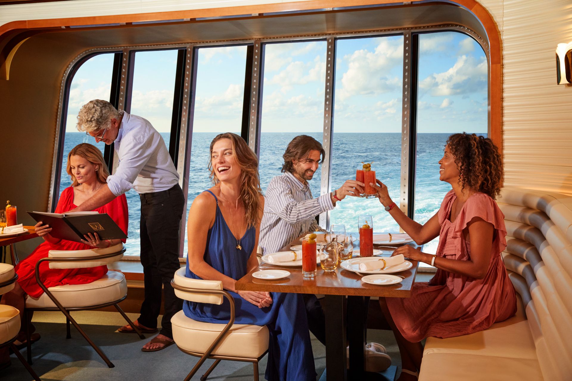Friends toasting mimosas over the ocean